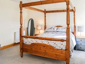 a wooden bed with a wooden frame in a bedroom at West Lanegate Farmhouse in Amisfield Town