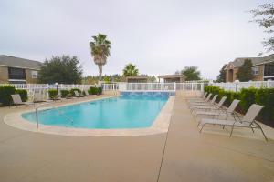 a large swimming pool with lounge chairs and a palm tree at Park Avenue 109 in Foley