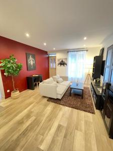 sala de estar con sofá blanco y pared roja en Le Domaine Des Yèbles - Appartement Calme et élégant, en Avon