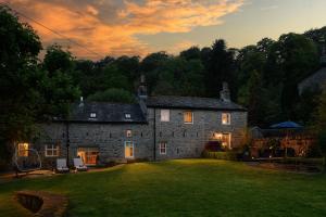 an old stone house with a large yard at sunset at Carrholme Cottage in Settle