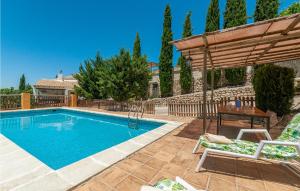 a swimming pool with a wooden umbrella and chairs at Stunning Home In Montefrio With Kitchen in Montefrío