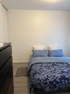 Schlafzimmer mit einem Bett mit blauer Bettwäsche und einer Kommode in der Unterkunft Moderne & LUXURY T2 Paris la défense in Puteaux
