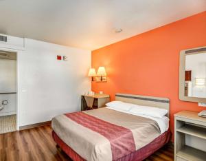 a hotel room with a bed with an orange wall at Motel 6-Tracy, CA in Tracy