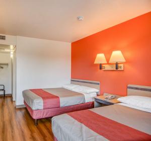 a hotel room with two beds and an orange wall at Motel 6-Tracy, CA in Tracy