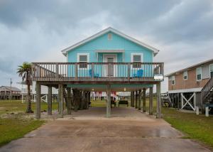 a blue house on wooden posts with a porch at Breaking Even House in Fort Morgan