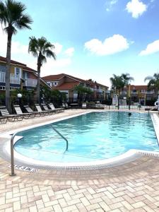 a large swimming pool with chairs and palm trees at Enchanting Escape 3 Bedroom Minutes from Disney! in Kissimmee