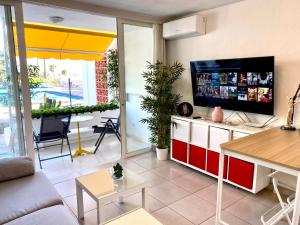 a living room with a flat screen tv and a table at Adeje Beach Holiday Home Viña del Mar in Playa Fañabe