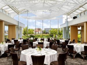 um salão de banquetes com mesas e cadeiras brancas e janelas grandes em Inn at Laurel Point em Victoria