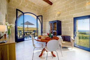 una sala da pranzo con tavolo, sedie e vista sull'oceano di Dar Il-Bahar Holiday home a San Lawrenz