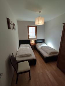 1 dormitorio con 2 camas, silla y ventana en Kerstin 5 by SMR Rauris Apartments - inc Spa and National Summercard - near Gondola, en Rauris