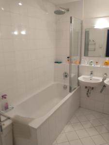 Baño blanco con bañera y lavamanos en Kerstin 5 by SMR Rauris Apartments - inc Spa and National Summercard - near Gondola, en Rauris