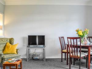 a living room with a table and a tv at The Bungalow in Carnoustie