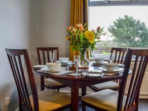 a dining room table with a vase of flowers on it at The Bungalow in Carnoustie