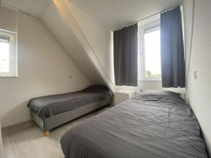 a bedroom with two beds and two windows at Villa Christina in Stevensweert