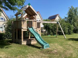 een houten speeltuin met een glijbaan in een tuin bij Villa Christina in Stevensweert