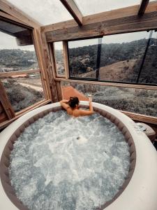 a woman sitting in a jacuzzi tub in a house at Pousada Vale da Magia in Praia do Rosa