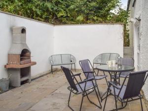 a patio with a table and chairs and an oven at Guildford Bridge Cottage in Llangwm