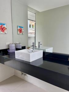 La salle de bains est pourvue d'un lavabo blanc et d'un miroir. dans l'établissement Villa Nirwana - Jasmin 3BR with private pool, à Ban Ang Thong