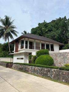 une maison blanche avec un palmier derrière un mur dans l'établissement Villa Nirwana - Jasmin 3BR with private pool, à Ban Ang Thong