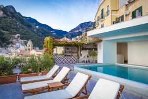 a hotel with a swimming pool and chairs and mountains at Hotel Marina Riviera in Amalfi
