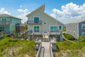 a house with a boardwalk leading to a house at Slow Your Roll in Topsail Beach