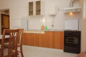 eine Küche mit Holzschränken und einem schwarzen Herd in der Unterkunft Apartments by the sea Zaglav, Dugi otok - 8145 in Zaglav