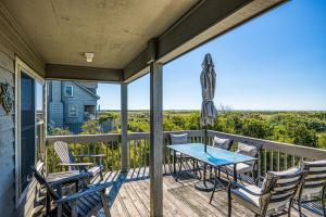 a balcony with a table and chairs and an umbrella at Baylin A in Topsail Beach