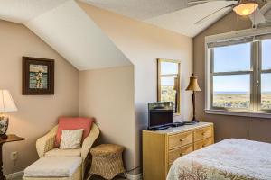 um quarto com uma cama, uma cadeira e uma janela em Baylin A em Topsail Beach
