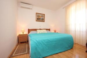 a bedroom with a bed with a blue blanket on it at Apartments by the sea Sutomiscica, Ugljan - 8474 in Sutomišćica