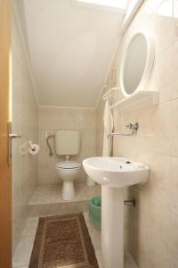een badkamer met een witte wastafel en een toilet bij Apartments with a parking space Kukljica, Ugljan - 8237 in Kukljica