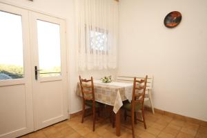 a dining room with a table and chairs and a window at Apartment Kukljica 8237c in Kukljica +17 photos