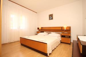 a bedroom with a large bed with a wooden headboard at Apartment Kukljica 8237b in Kukljica