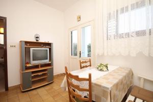 a dining room with a table and a television at Apartment Kukljica 8237c in Kukljica