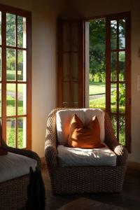 a chair with an orange pillow in a room with windows at 5TO PISO by Bourbon Hostal in Juayúa