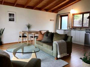 een woonkamer met een bank en een tafel bij Adrift In Golden Bay- Absolute Beachfront Villas in Collingwood