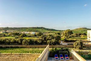 a view of a city from a balcony with blue chairs at Four Winds Holiday Home in Kerċem