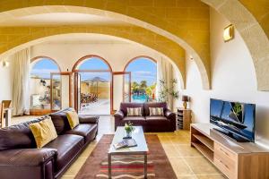 a living room with a couch and a tv at Four Winds Holiday Home in Kerċem