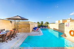 a swimming pool with a table and chairs and an umbrella at Four Winds Holiday Home in Kerċem