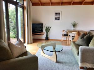 un soggiorno con divano e tavolo in vetro di Adrift In Golden Bay- Absolute Beachfront Villas a Collingwood