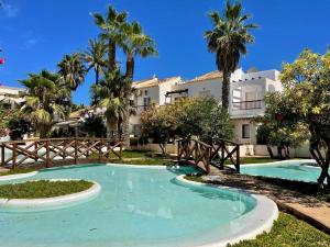 a swimming pool in front of a building with palm trees at Inviting holiday home in Roquetas de Mar with terrace in Roquetas de Mar