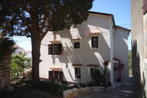 a white house with a tree in front of it at Apartments and rooms with parking space Cunski, Losinj - 2498 in Cunski