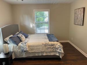 a bedroom with a bed with blue pillows and a window at Stylish and Cozy Retreat in Buford