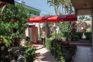 a patio with a red umbrella and some plants at Pousada Navegantes in Navegantes