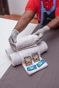 a person in gloves preparing towels on a table at Pousada Navegantes in Navegantes