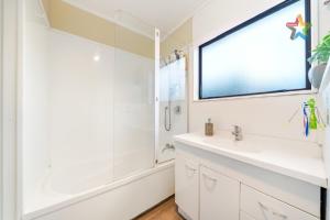 baño blanco con lavabo y ventana en Trentham Gem, en Upper Hutt