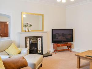 a living room with a fireplace and a tv at The Moorings in Lochmaben