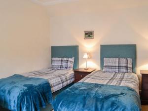 a bedroom with two beds with blue sheets at The Moorings in Lochmaben
