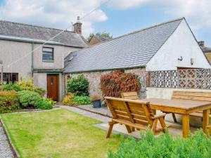 a wooden picnic table in the garden of a house at The Moorings in Lochmaben