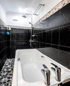 a bathroom with a white sink and black tiles at CHIEF'S VILLA Rentals Malapascua Island in Malapascua Island