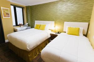 two beds in a hotel room with yellow pillows at Hotel Richland LES in New York